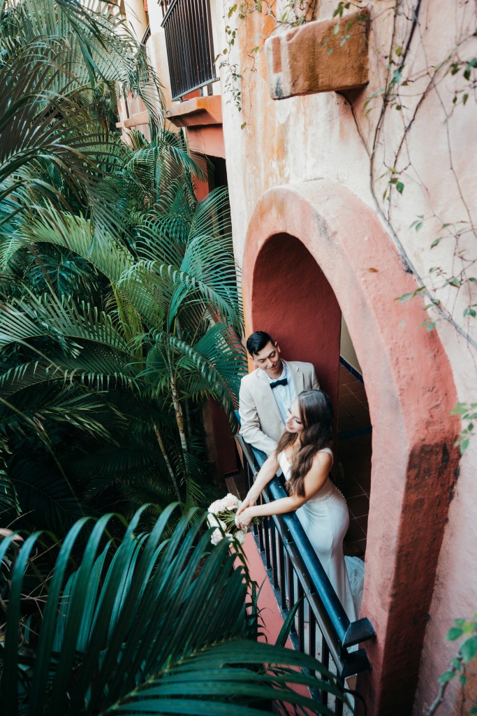 bride and groom standing in an balcony of a Mexican hotel on their wedding day