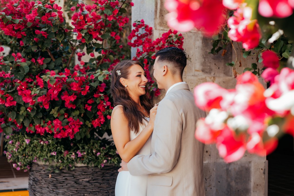 bride and groom standing by flowers in mexico