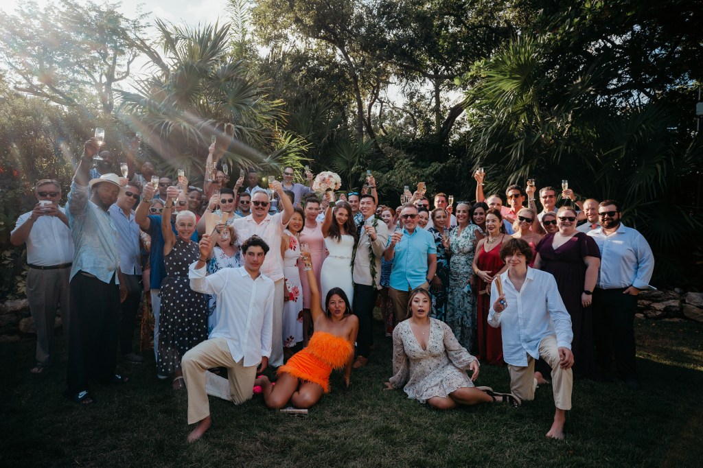 All wedding guests cheers together for a portrait at a destination wedding 